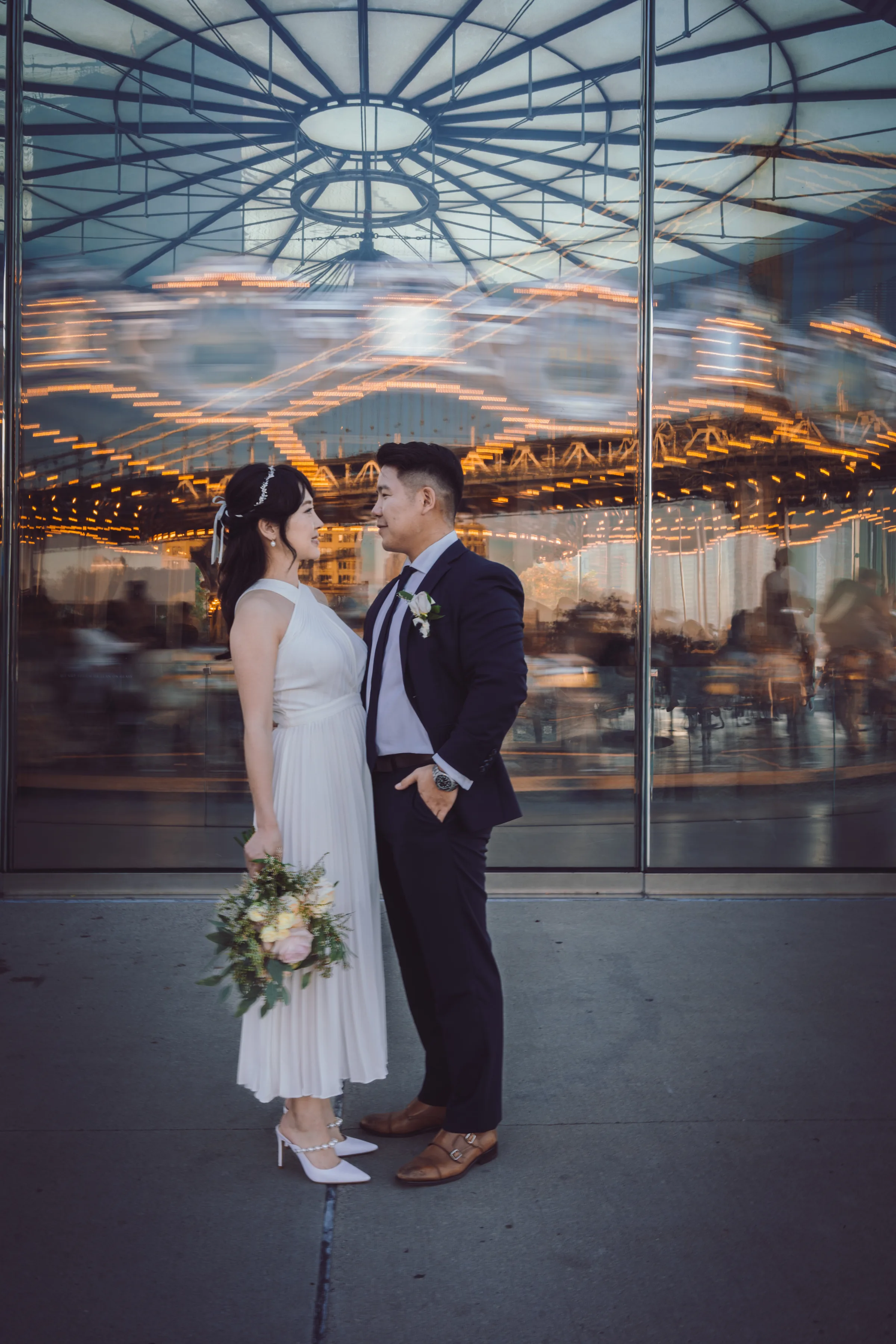Bride and groom embracing in front of an illuminated carousel