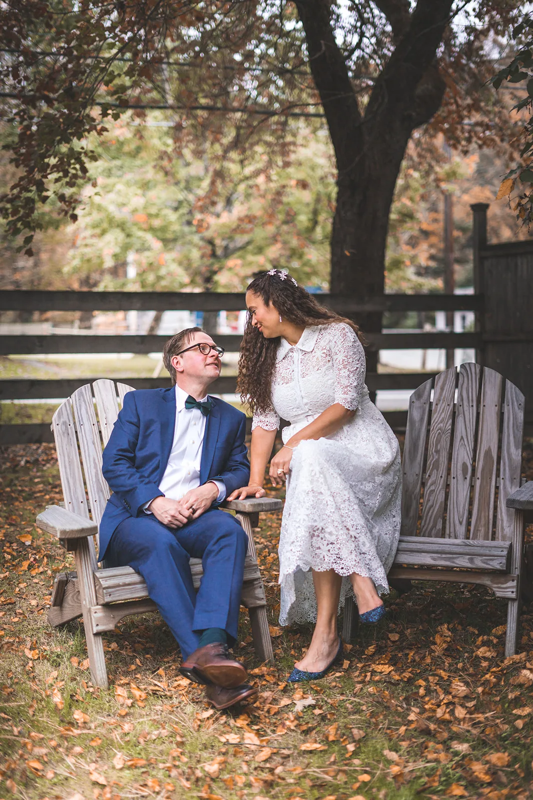 Newlyweds seated together on a garden bench beneath the trees