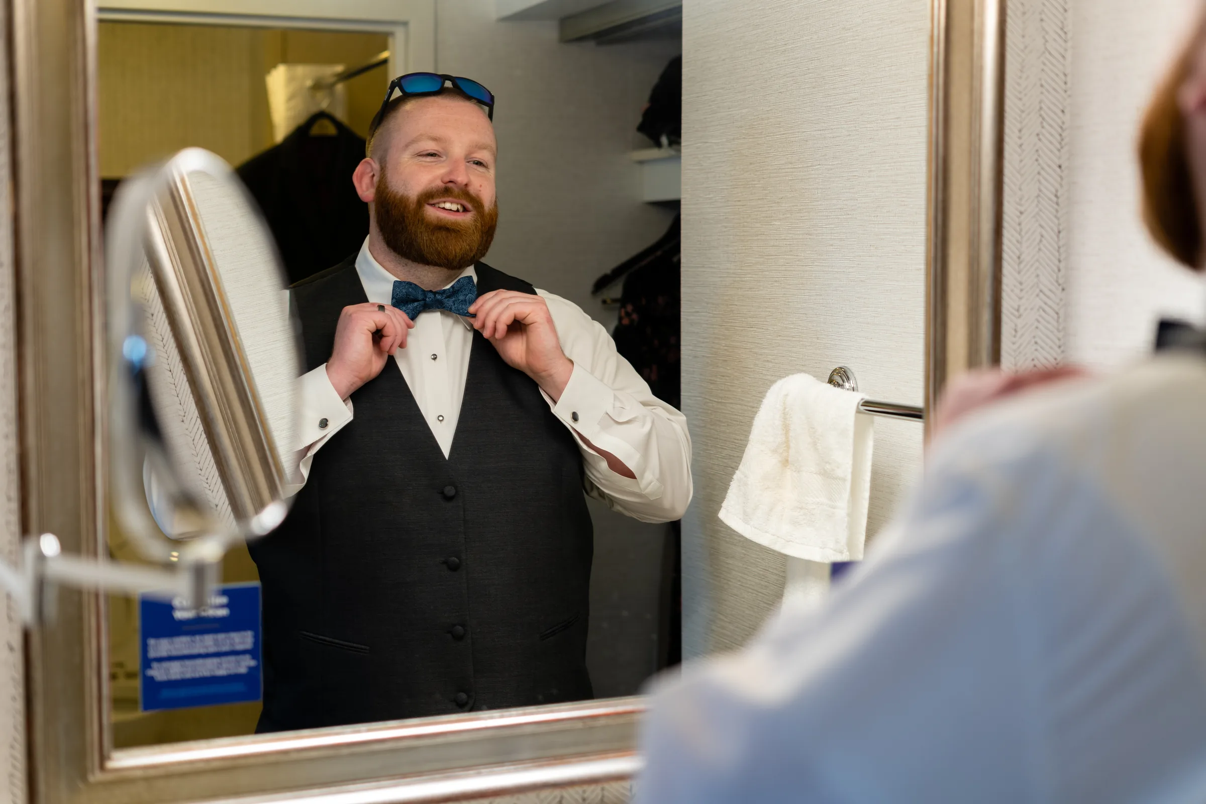 Groom adjusting his tie in a mirror while preparing for the wedding