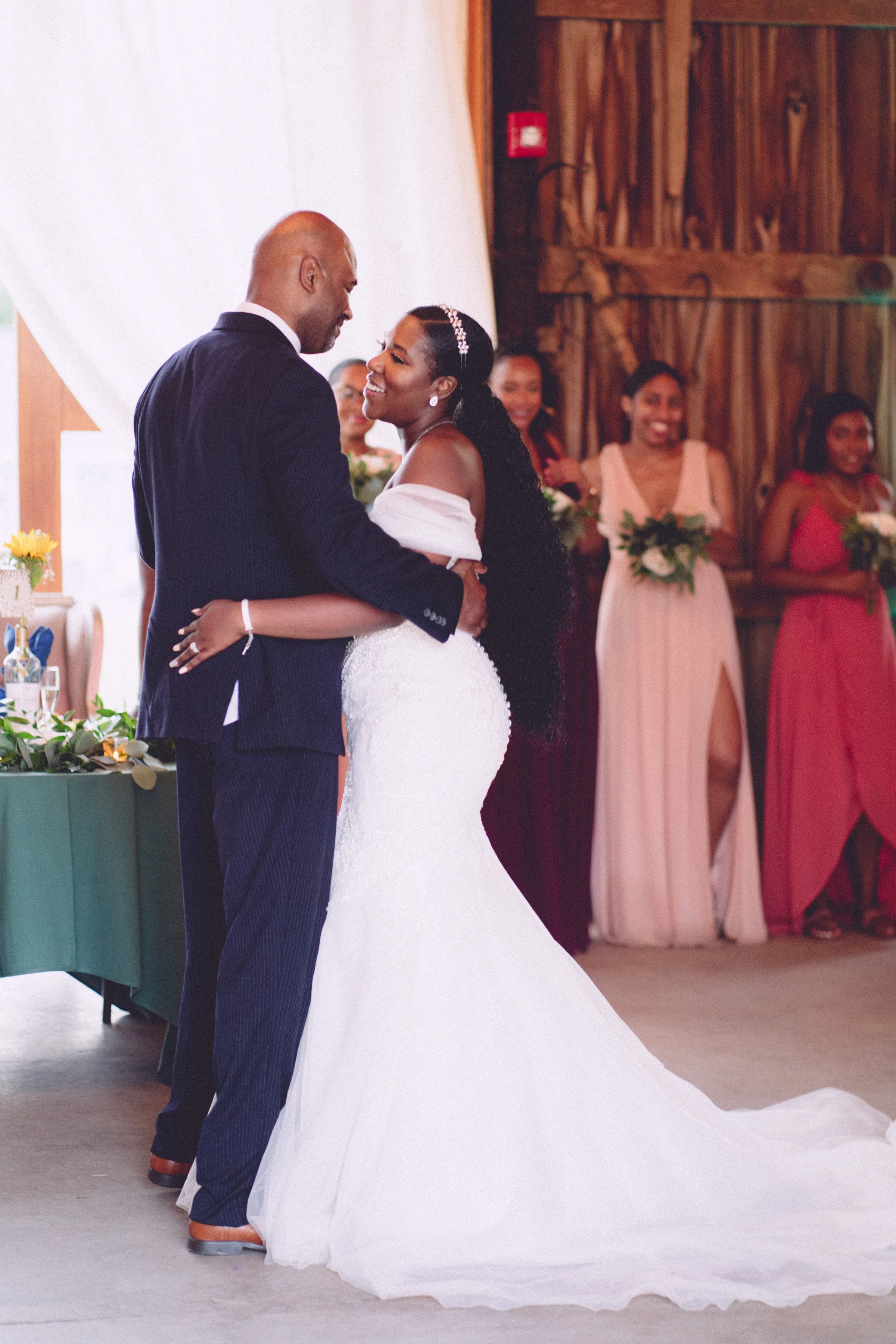 Bride and groom embracing indoors with their wedding party behind them