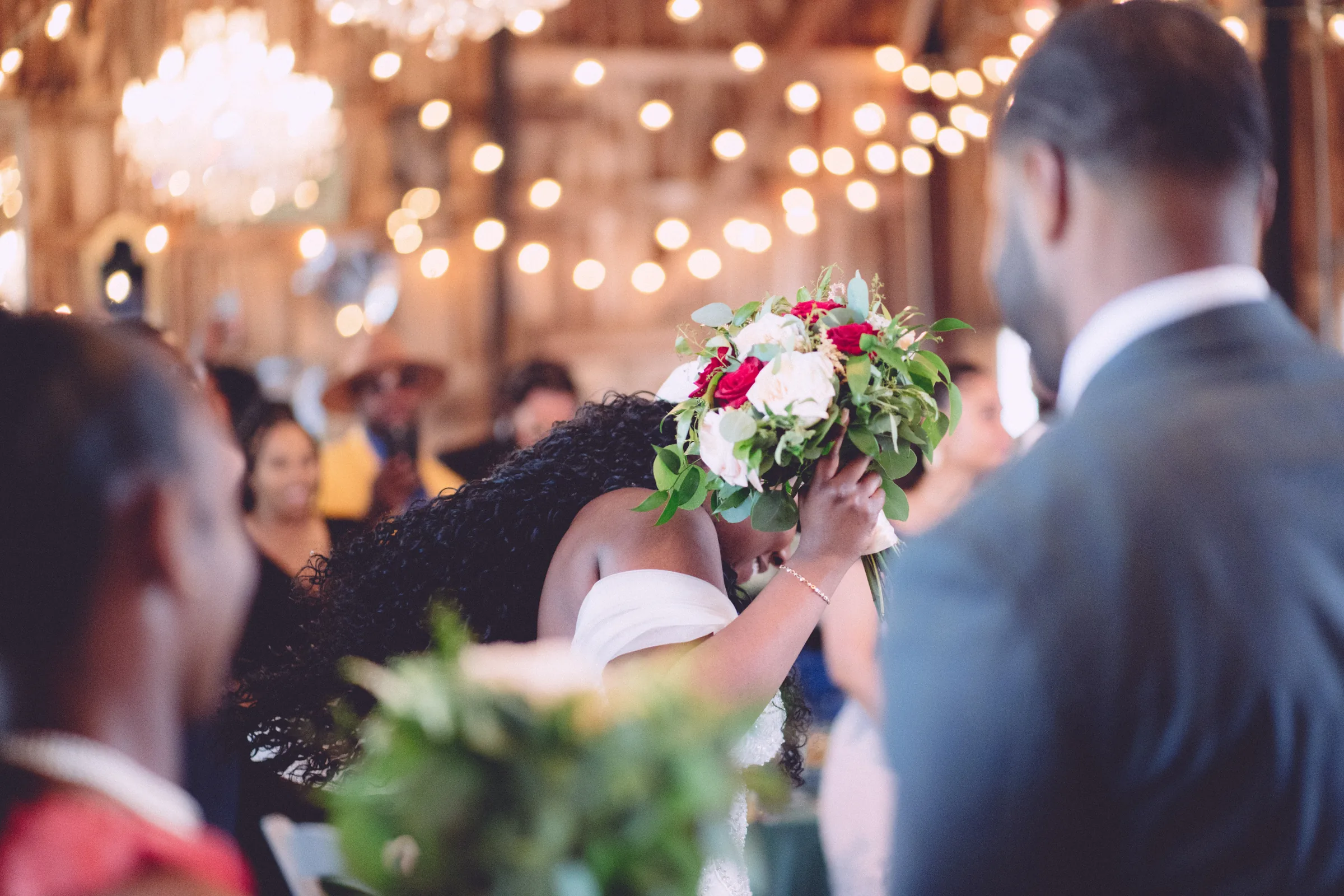 Bride bowing her head behind her bouquet during the wedding ceremony
