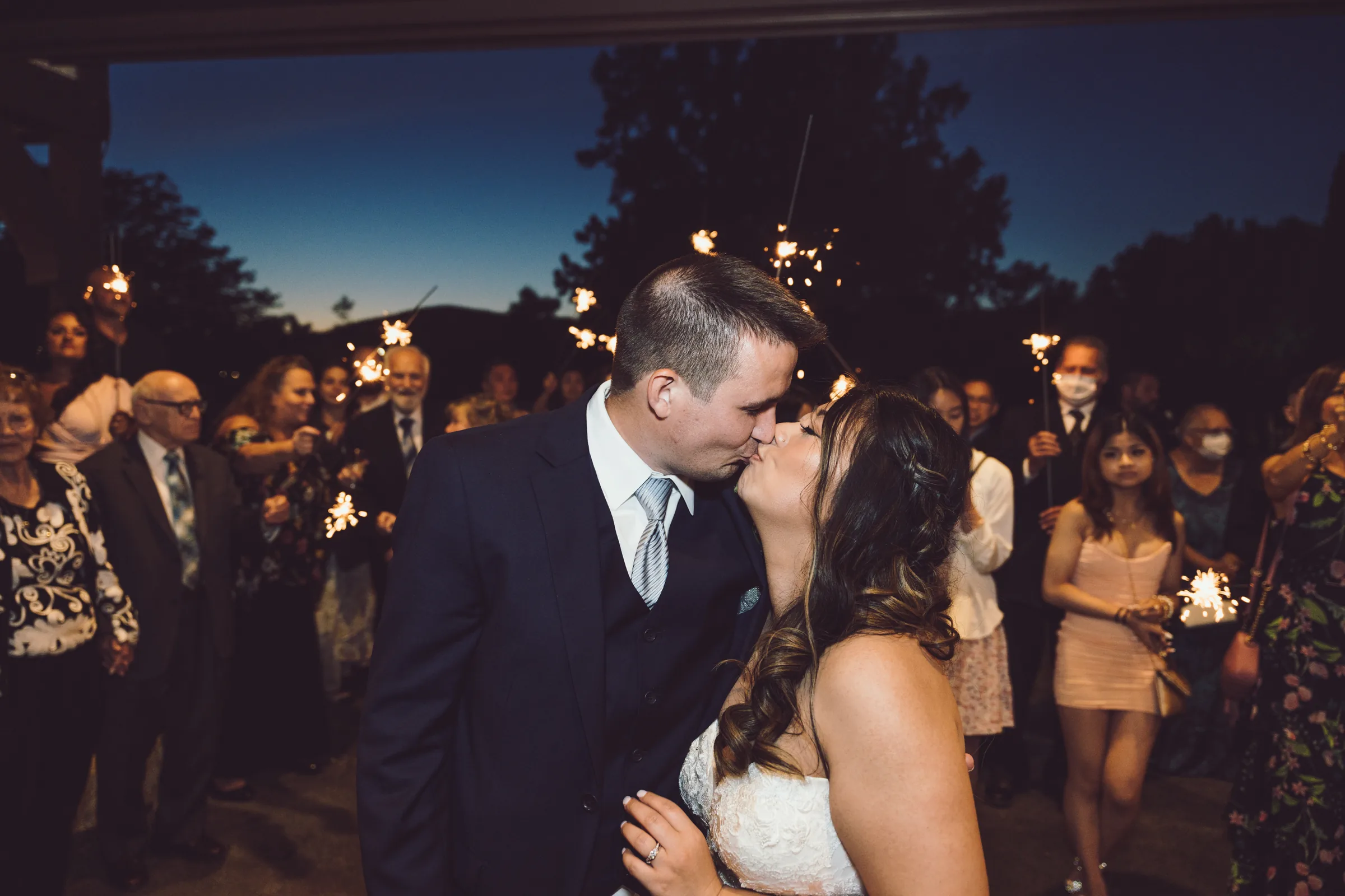 Newlyweds kissing in front of their guests at an evening wedding reception